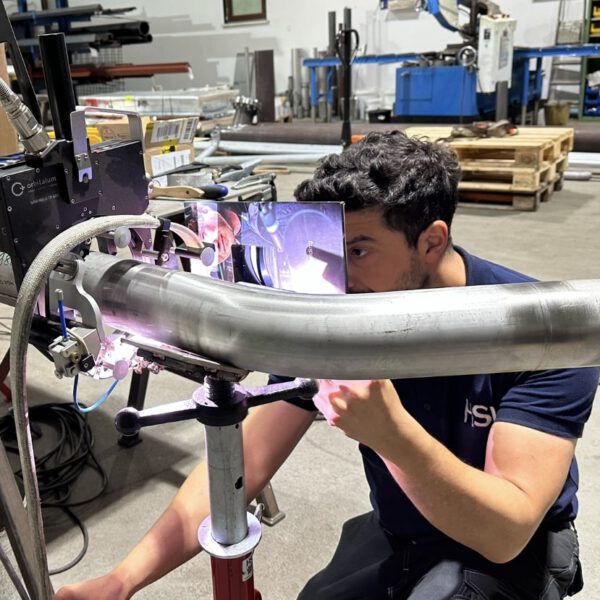 Gruppenfoto eines Montageteams in Warnwesten vor einer Industrieanlage.